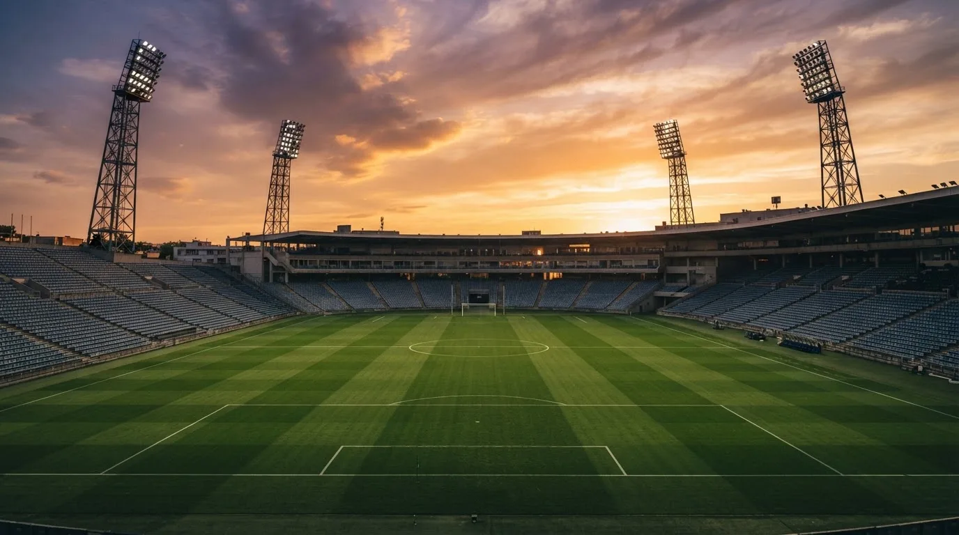 Un estadio de fútbol vacío con torres de iluminación al atardecer