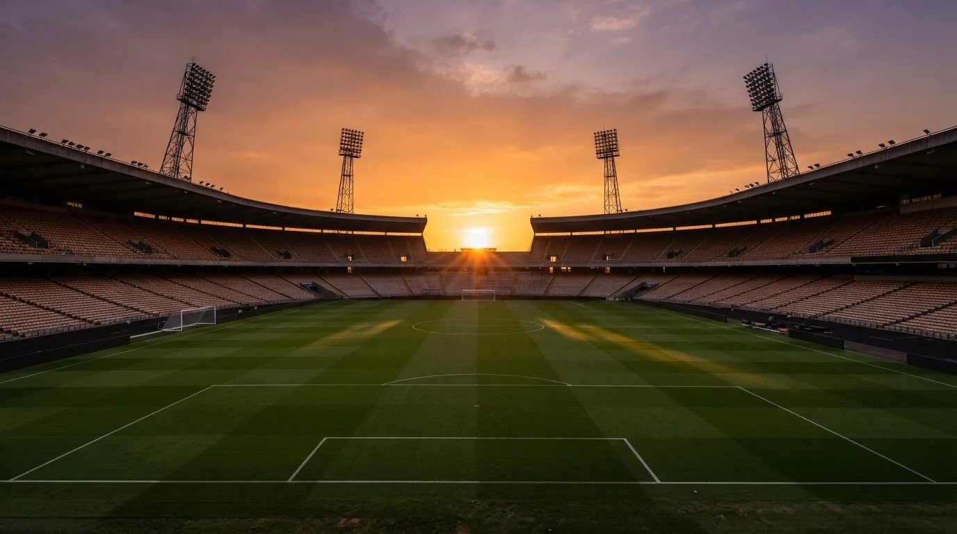 Un estadio de fútbol vacío con torres de iluminación al atardecer