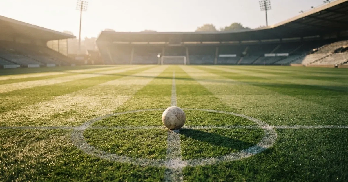 Un balón en el punto central de un campo de césped a la luz de la mañana