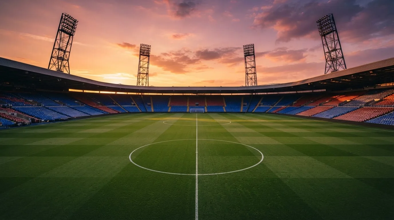 Un estadio de fútbol vacío con torres de iluminación al atardecer
