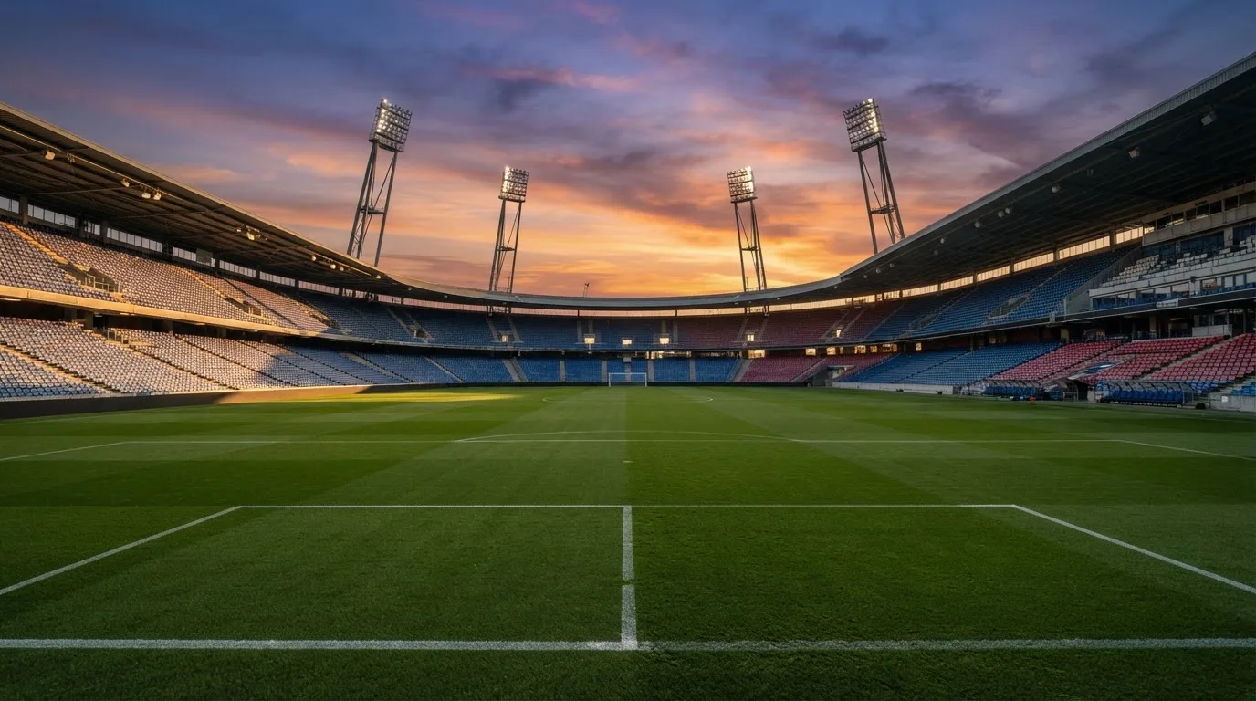 Un estadio de fútbol vacío con torres de iluminación al atardecer