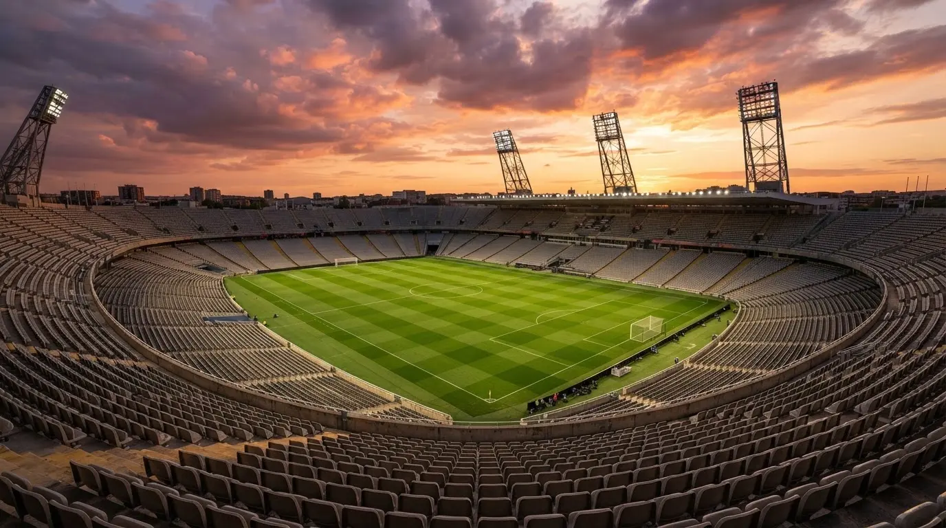 Un estadio de fútbol vacío con torres de iluminación al atardecer