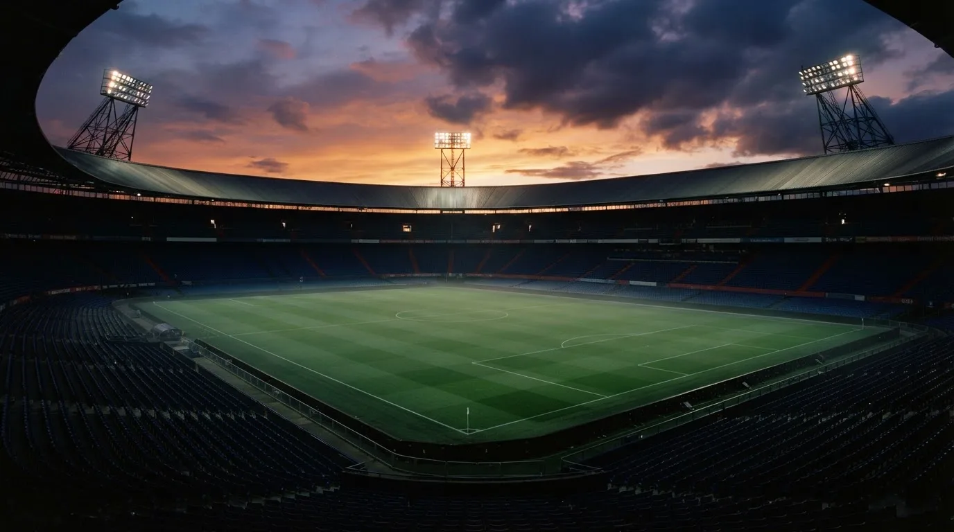 Un estadio de fútbol vacío con torres de iluminación al atardecer