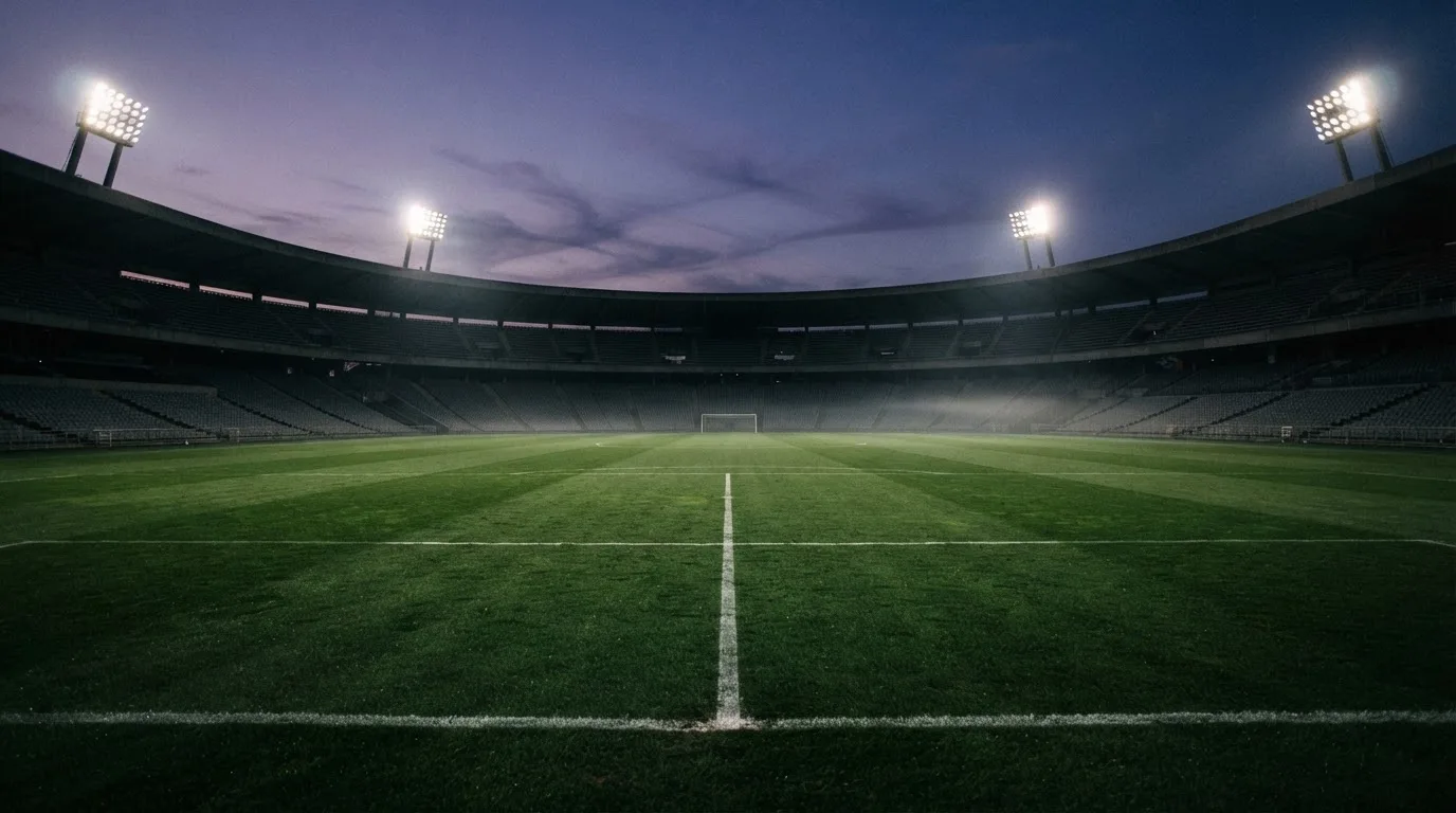 Un estadio de fútbol vacío con torres de iluminación al atardecer